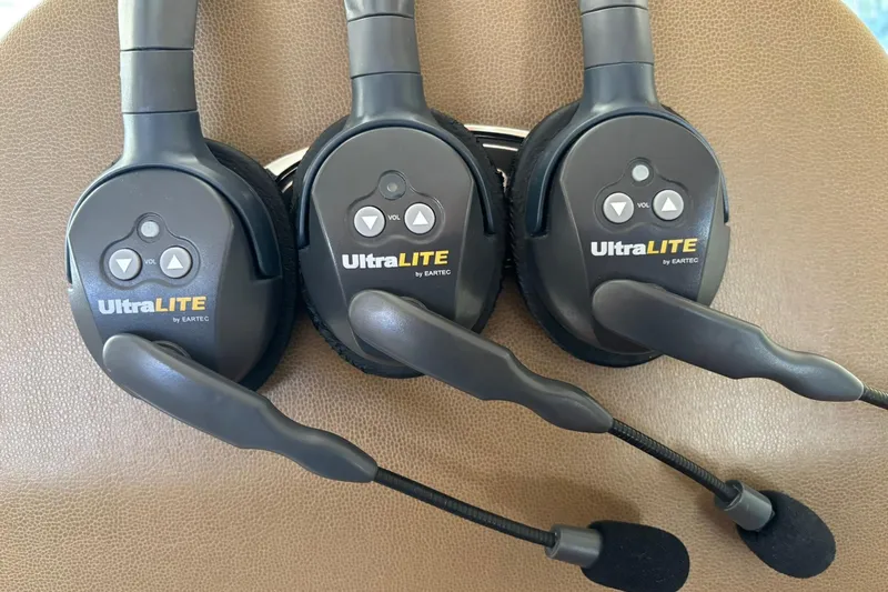 Dolce Far Niente Yacht Photos Pics Three UltraLITE headsets with microphones on a brown surface.