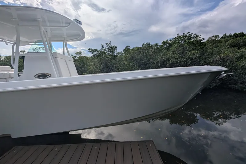  Yacht Photos Pics 2013 Contender 35 LS boat docked near lush greenery under a cloudy sky.