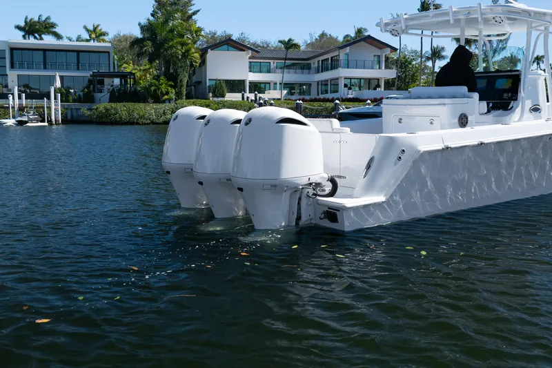  Yacht Photos Pics 2013 Contender 35 LS boat with triple outboard engines on a calm waterfront.