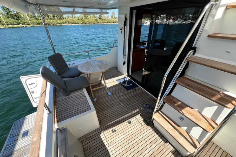 Billy Yacht Photos Pics 2014 Beneteau Swift Trawler 50 deck with seating, table, and stairs by the water.