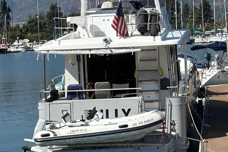 Billy Yacht Photos Pics 2014 Beneteau Swift Trawler 50 docked with dinghy, American flag, and scenic marina backdrop.