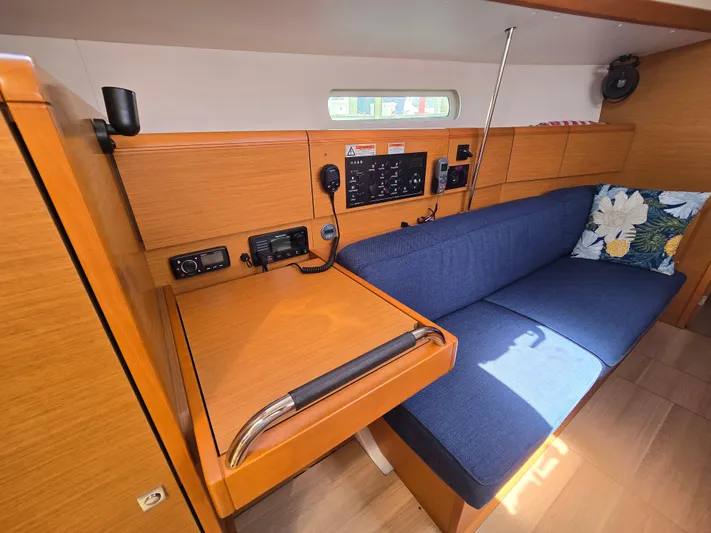 Yacht Photos Pics 2017 Jeanneau Sun Odyssey 389 interior with navigation station and blue cushioned seating.