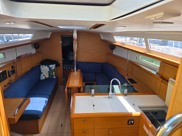  Yacht Photos Pics Interior of 2017 Jeanneau Sun Odyssey 389 sailboat with blue seating and wooden finishes.