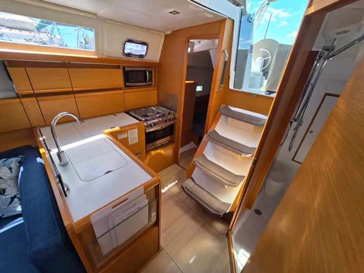  Yacht Photos Pics Interior of 2017 Jeanneau Sun Odyssey 389 sailboat, featuring modern kitchen and wooden cabinetry.