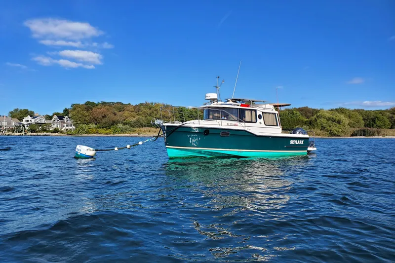 Skylark Yacht Photos Pics 2025 Ranger Tugs R23 boat anchored on calm water under a clear blue sky.