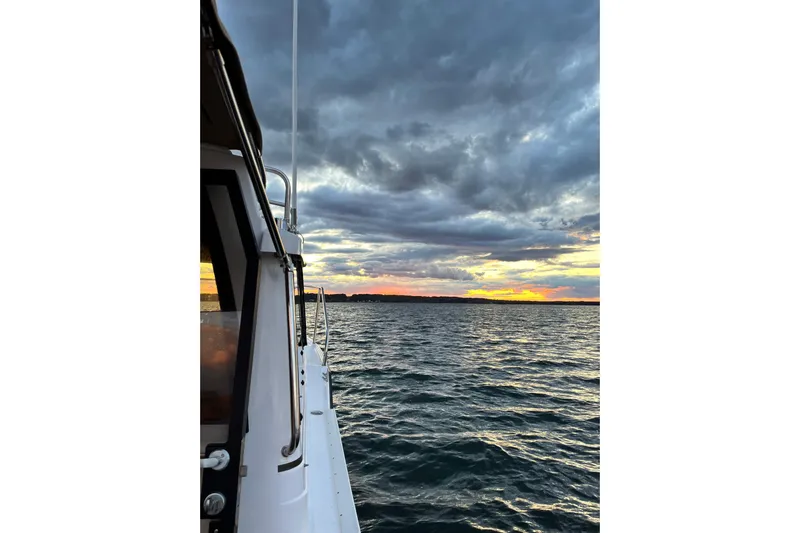 Skylark Yacht Photos Pics 2025 Ranger Tugs R23 boat on water at sunset with dramatic clouds.