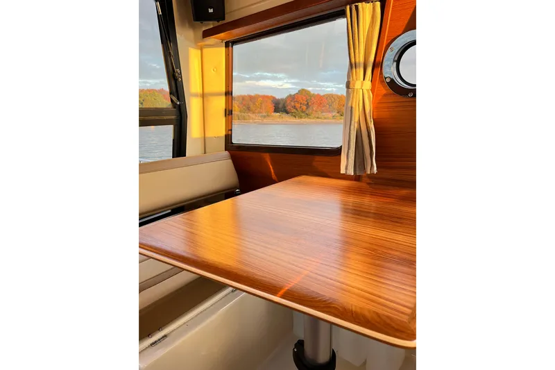Skylark Yacht Photos Pics Interior of 2025 Ranger Tugs R23 boat with wooden table and scenic window view.