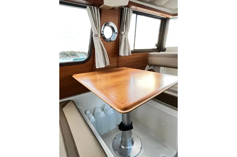 Skylark Yacht Photos Pics Interior of 2025 Ranger Tugs R23, featuring a wooden table and windows with curtains.