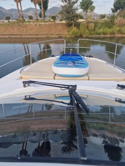  Yacht Photos Pics 2008 Jeanneau Prestige 38 S yacht with paddleboard on deck, docked by scenic waterway.