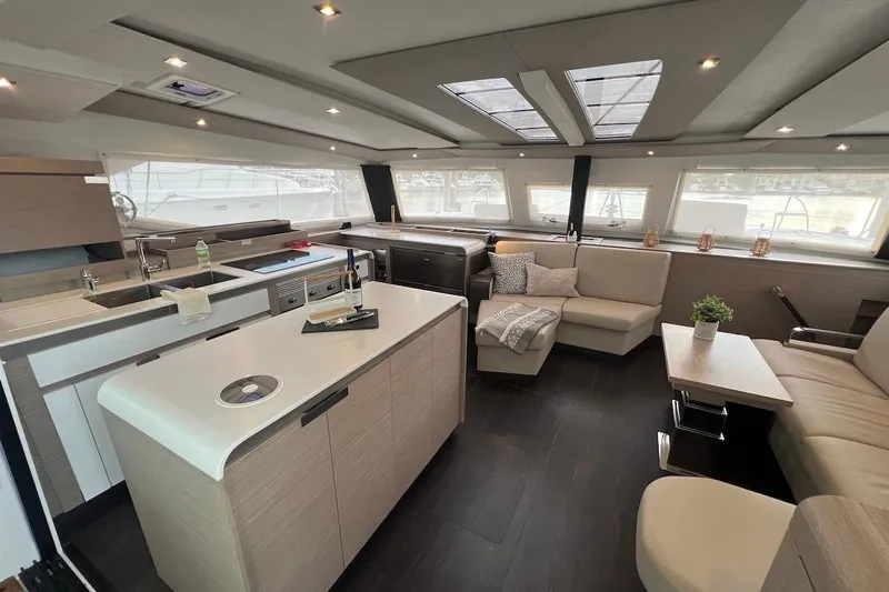 Amajen Yacht Photos Pics Luxurious interior of 2022 Fountaine Pajot Aura 51 catamaran with modern kitchen and seating area.