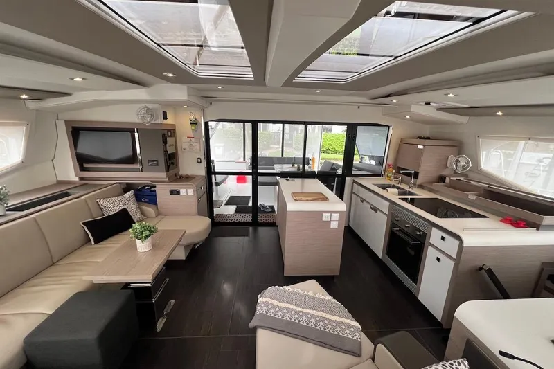 Amajen Yacht Photos Pics Luxurious interior of 2022 Fountaine Pajot Aura 51 catamaran with modern kitchen and seating area.