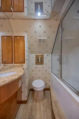 Volare Yacht Photos Pics Luxurious bathroom in 2006 Hatteras 64 Motor Yacht with modern fixtures and wood accents.