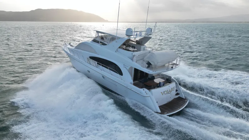 Volare Yacht Photos Pics 2006 Hatteras 64 Motor Yacht cruising on open water at sunset.