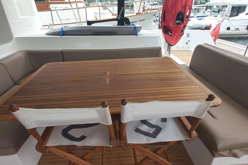 Amea Yacht Photos Pics Outdoor seating area on a 2014 Lagoon 52 F yacht with wooden table and cushioned benches.