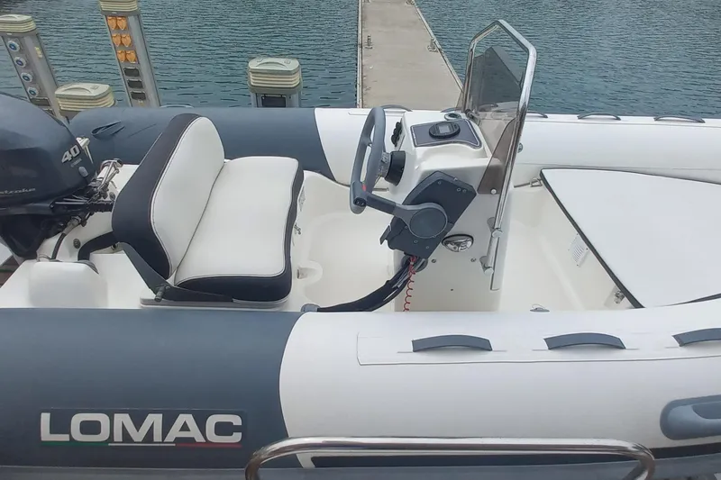 Amea Yacht Photos Pics Inflatable boat with steering console and seating, docked by the water.
