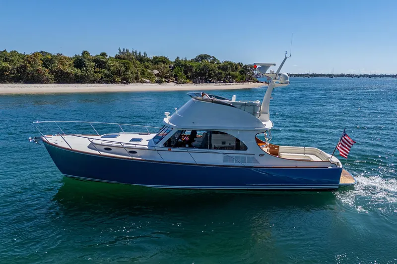 Twelve Bar Blues Yacht Photos Pics 2019 Hinckley Talaria 43 Flybridge yacht cruising on blue water near a sandy shoreline.