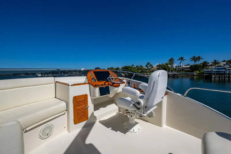 Twelve Bar Blues Yacht Photos Pics 2019 Hinckley Talaria 43 Flybridge helm with seating, overlooking serene waterfront and palm trees.