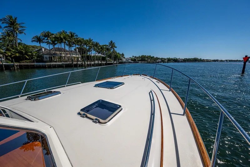 Twelve Bar Blues Yacht Photos Pics 2019 Hinckley Talaria 43 Flybridge cruising on a sunny day near palm-lined shore.