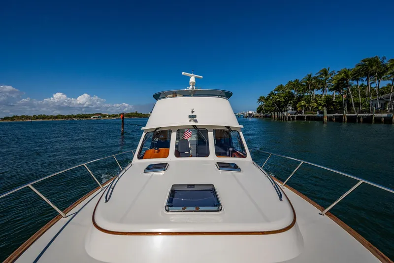 Twelve Bar Blues Yacht Photos Pics 2019 Hinckley Talaria 43 Flybridge yacht cruising on a sunny day with palm trees in the background.