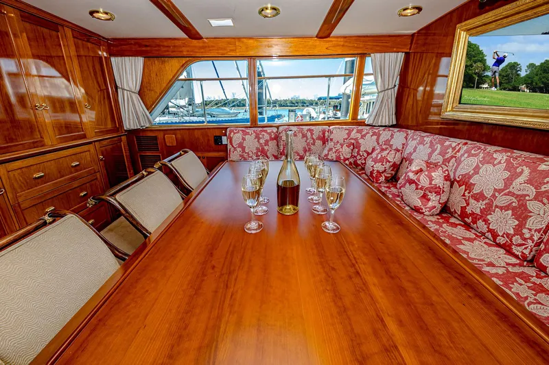 Diday Yacht Photos Pics Luxurious yacht dining area with wooden table, wine glasses, and floral seating, aboard a 1984 Burger 91.