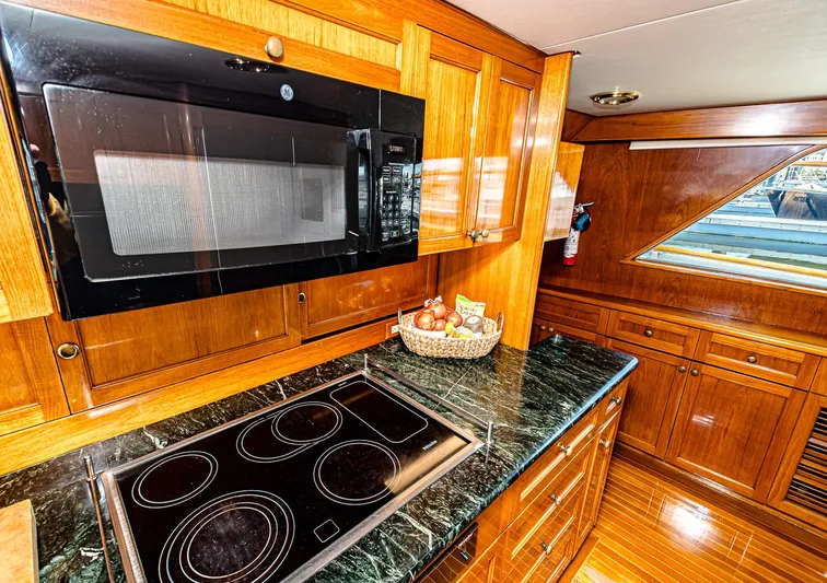 Diday Yacht Photos Pics Luxurious yacht kitchen with wooden cabinetry, black microwave, and sleek electric stovetop.