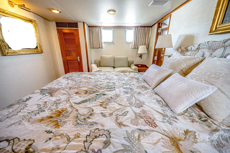Diday Yacht Photos Pics Luxurious bedroom interior on 1984 Burger 91 yacht, featuring elegant bedding and cozy seating area.