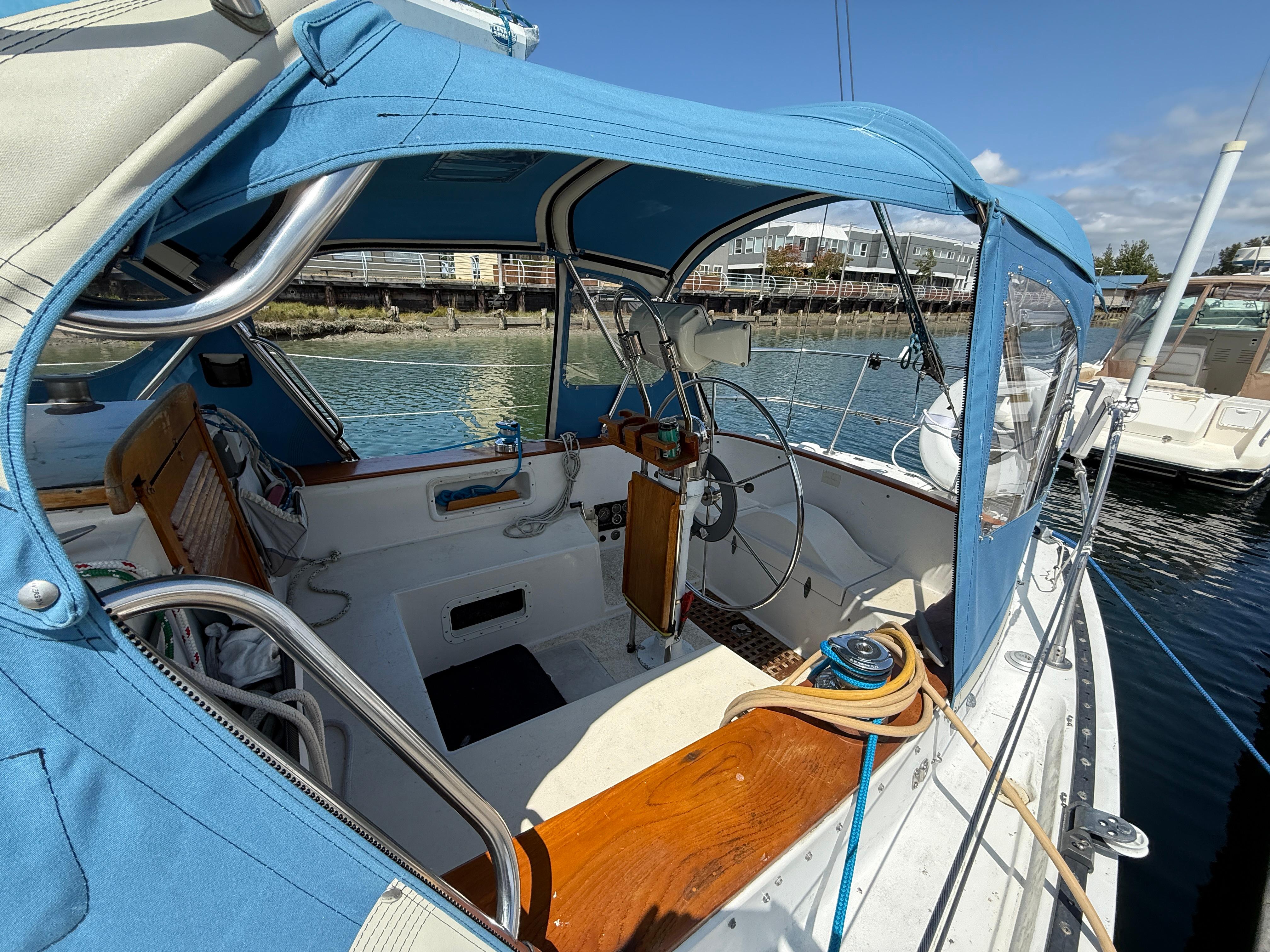 1984 Aloha 32 sailboat cockpit with blue canopy, docked by the water.