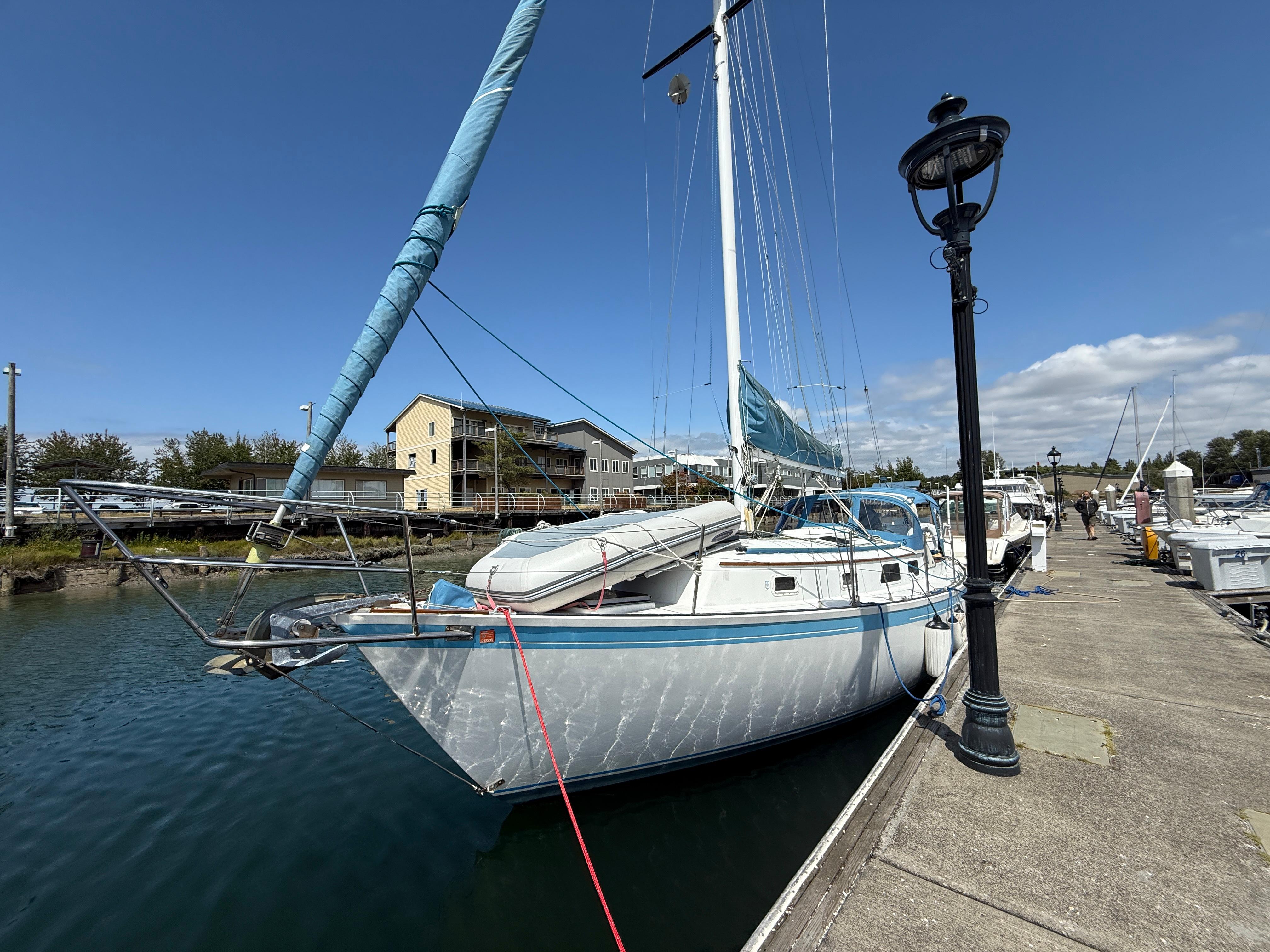 1984 Aloha 32 sailboat docked at marina under clear blue sky.