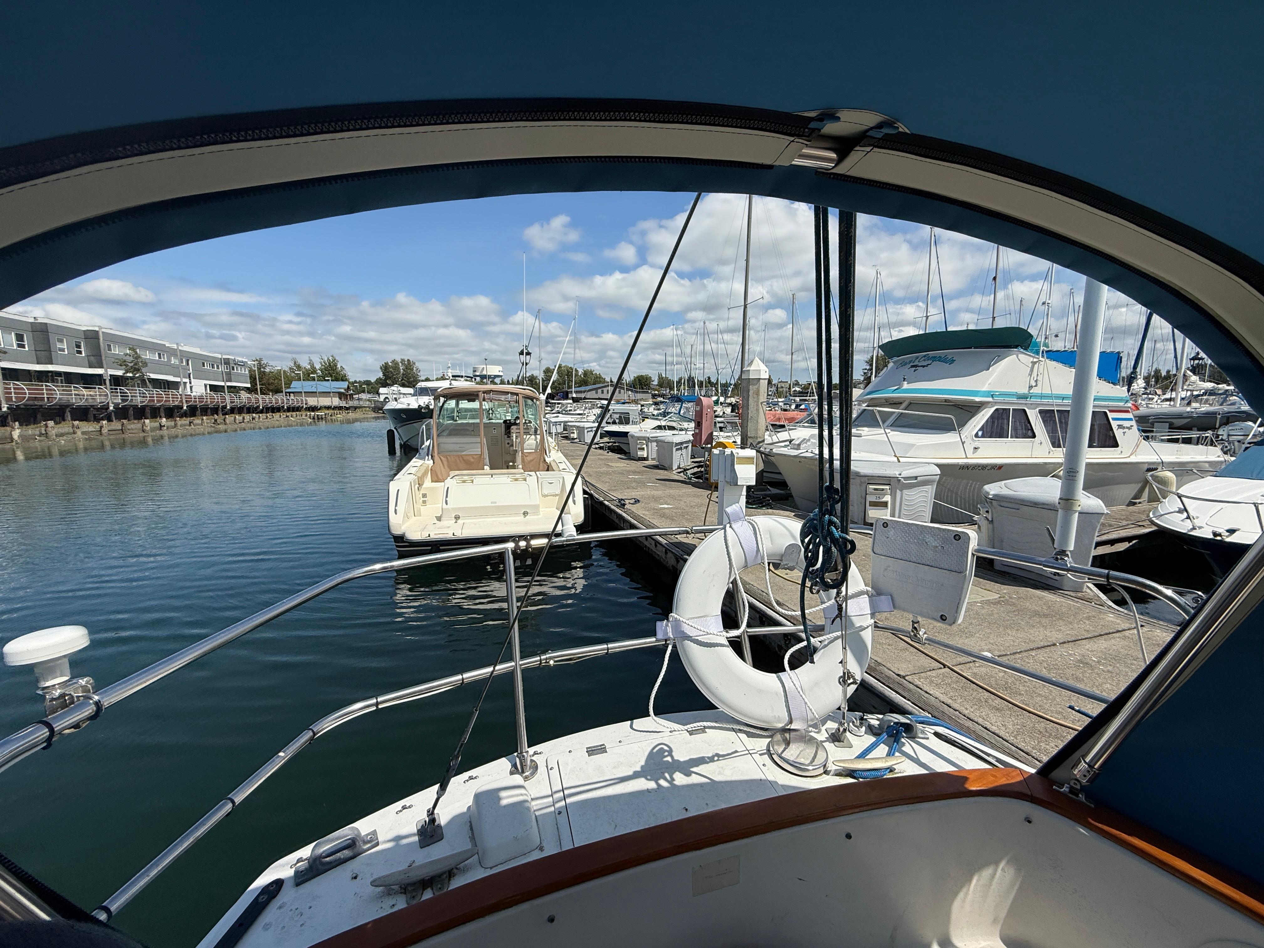 Aloha 32 sailboat docked at marina, showcasing serene waterfront and neighboring boats, 1984 model.