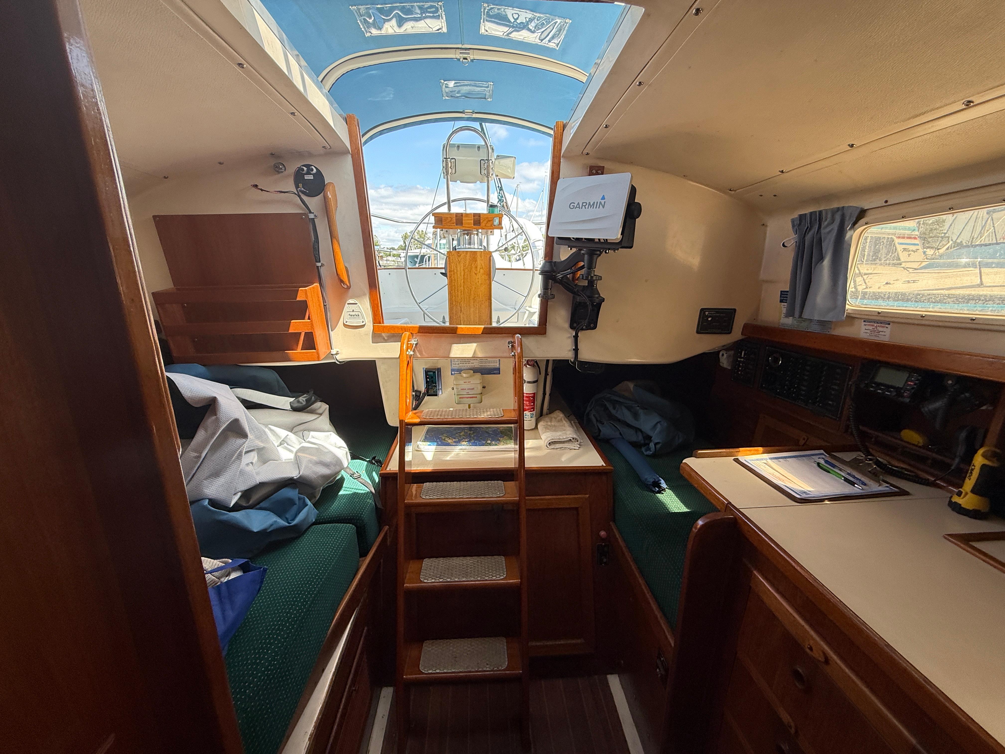 Interior of 1984 Aloha 32 sailboat with navigation equipment and cozy seating area.