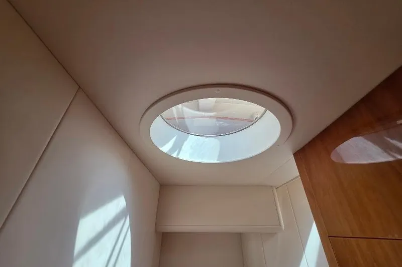 Blue Bird Yacht Photos Pics Circular skylight in 2008 Neptunus Flybridge MY yacht interior, illuminating wooden and white surfaces.