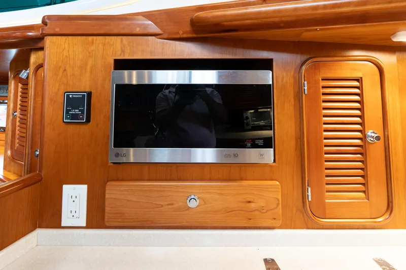 Solitude Yacht Photos Pics Interior of 2018 Passport Vista 545 Center Cockpit with built-in LG microwave and wooden cabinetry.