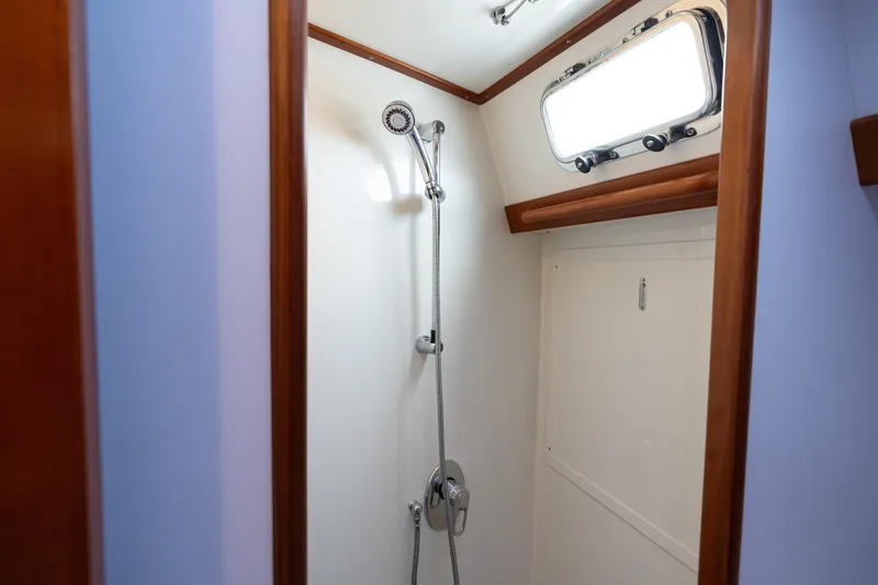 Solitude Yacht Photos Pics Shower area in 2018 Passport Vista 545 Center Cockpit yacht, featuring wooden trim and porthole.
