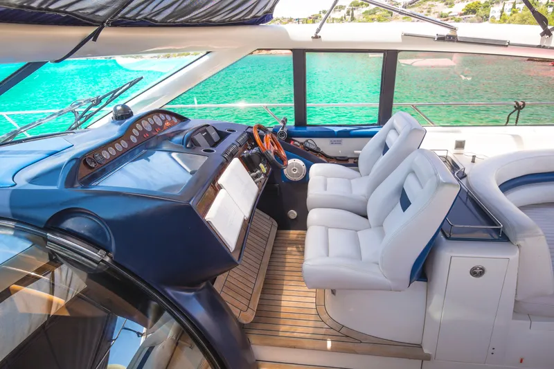  Yacht Photos Pics Luxurious 2004 Princess V65 yacht cockpit with white leather seats and wooden steering wheel.