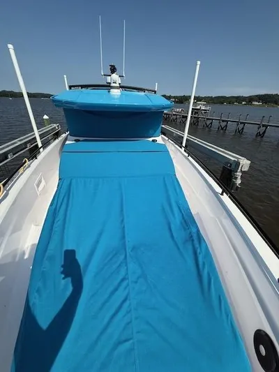  Yacht Photos Pics 2023 Axopar 37 Cross Cabin boat with blue cover on deck, docked by a calm lake.