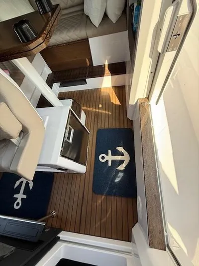  Yacht Photos Pics 2023 Axopar 37 Cross Cabin interior with wooden flooring and nautical-themed decor.