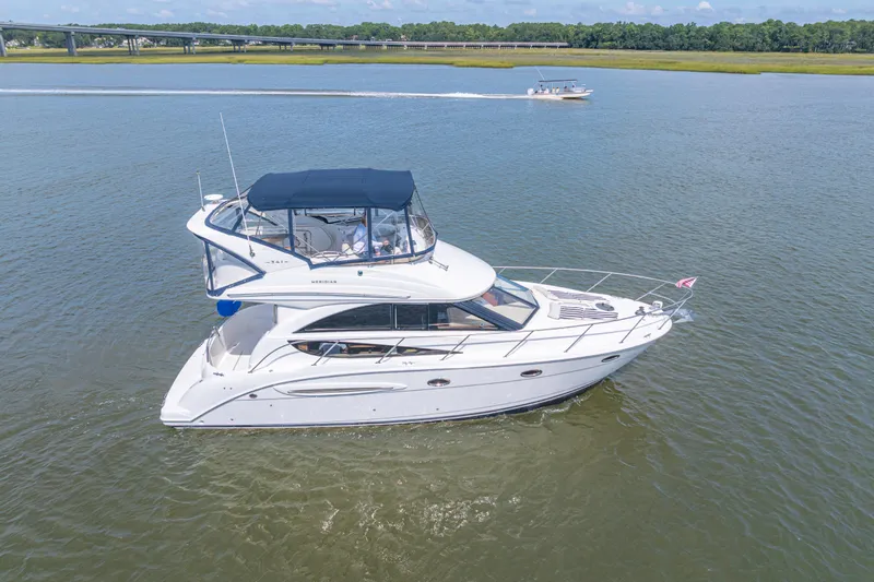  Yacht Photos Pics 2006 Meridian 341 Sedan yacht cruising on a calm river with scenic background.