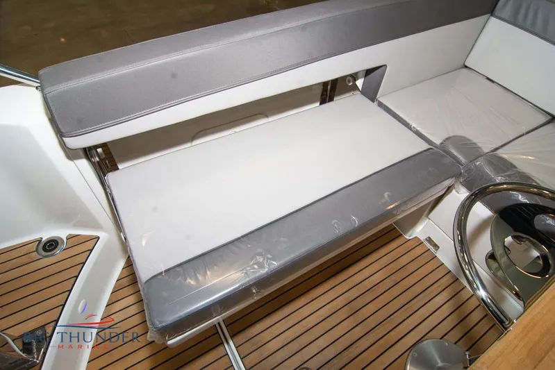  Yacht Photos Pics 2022 Jeanneau Leader 10.5 boat interior with cushioned seating and wooden flooring.