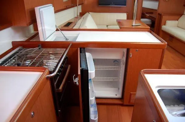 Le Reve Yacht Photos Pics Interior of 2008 Beneteau Oceanis 49 yacht kitchen with fridge, stove, and seating area.