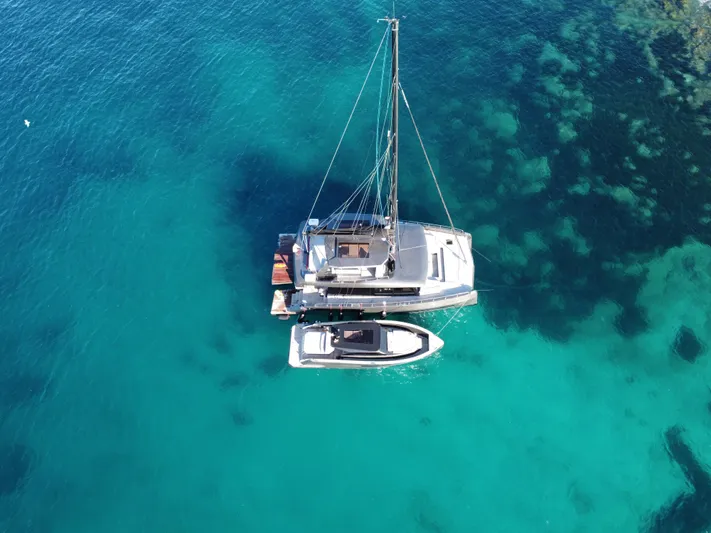 2026 Moon 60 Sail New Yacht Photos Pics Aerial view of 2026 Moon 60 Sail catamaran on clear turquoise water.