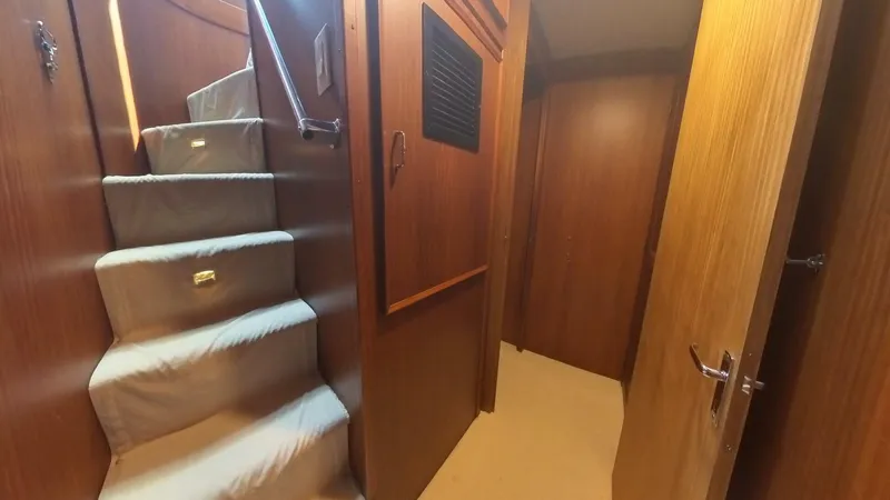 Carry On Yacht Photos Pics Interior hallway of 1982 Hatteras 65 LRC yacht with carpeted stairs and wooden paneling.