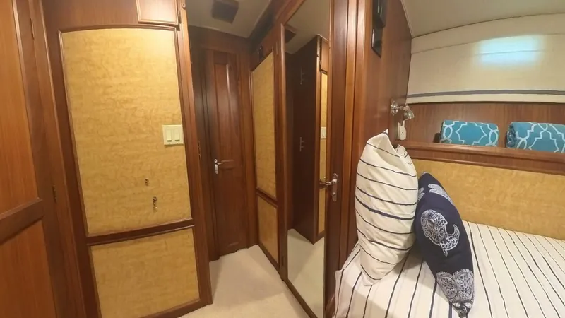 Carry On Yacht Photos Pics Interior of 1982 Hatteras 65 LRC yacht with wood paneling and striped bedding.