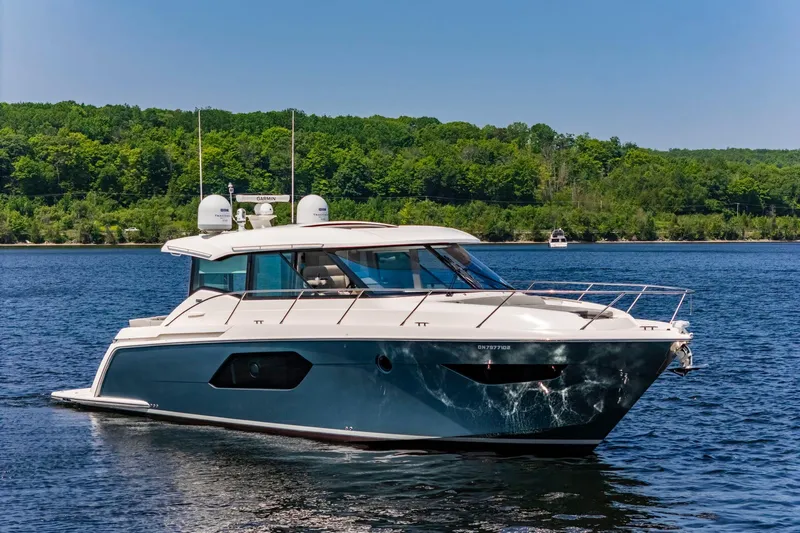  Yacht Photos Pics 2019 Tiara Yachts C49 Coupe cruising on a serene lake with lush green shoreline.