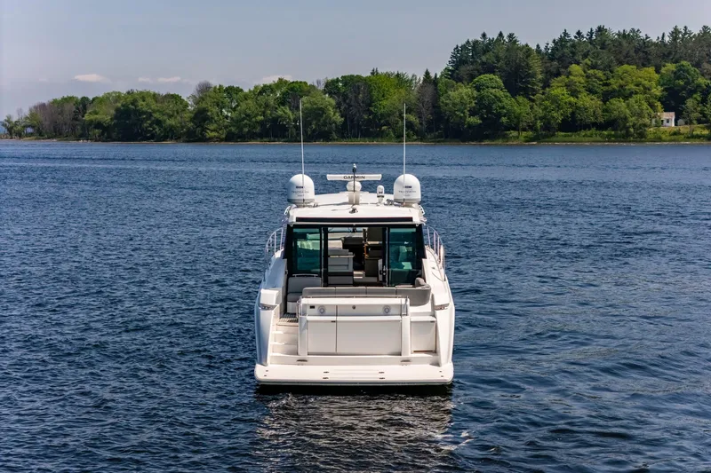  Yacht Photos Pics 2019 Tiara Yachts C49 Coupe on a serene lake with lush green shoreline.