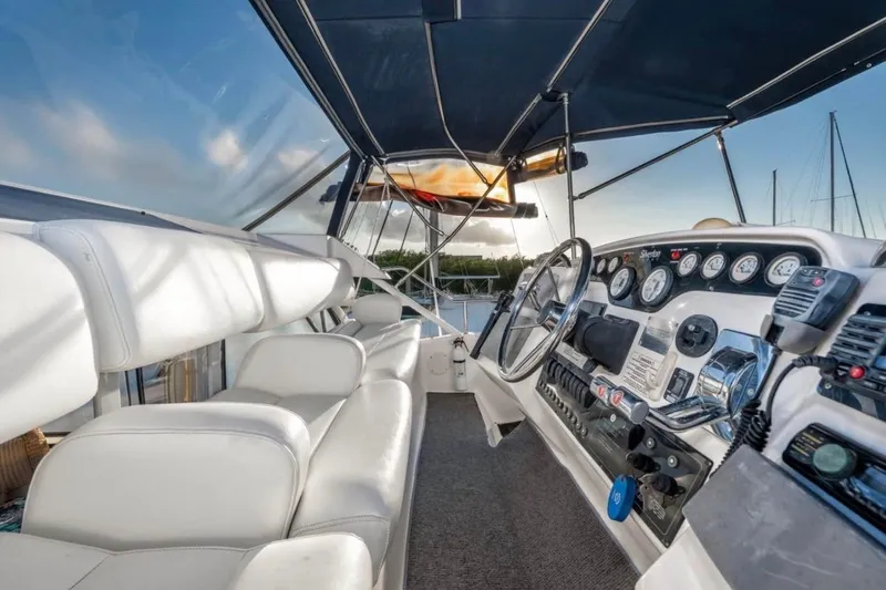  Yacht Photos Pics 1998 Silverton 372 Motor Yacht cockpit with white seating and control panel, under blue canopy.