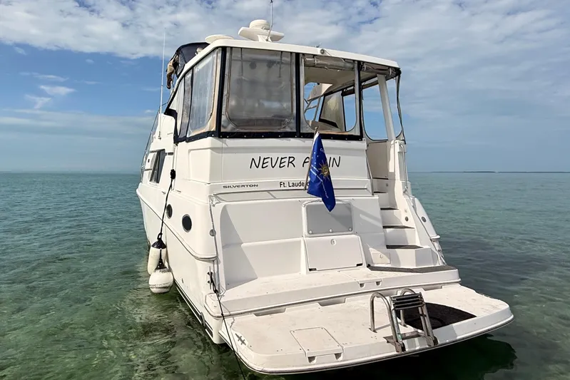  Yacht Photos Pics 1998 Silverton 40 Convertible yacht on calm sea, rear view with blue flag.