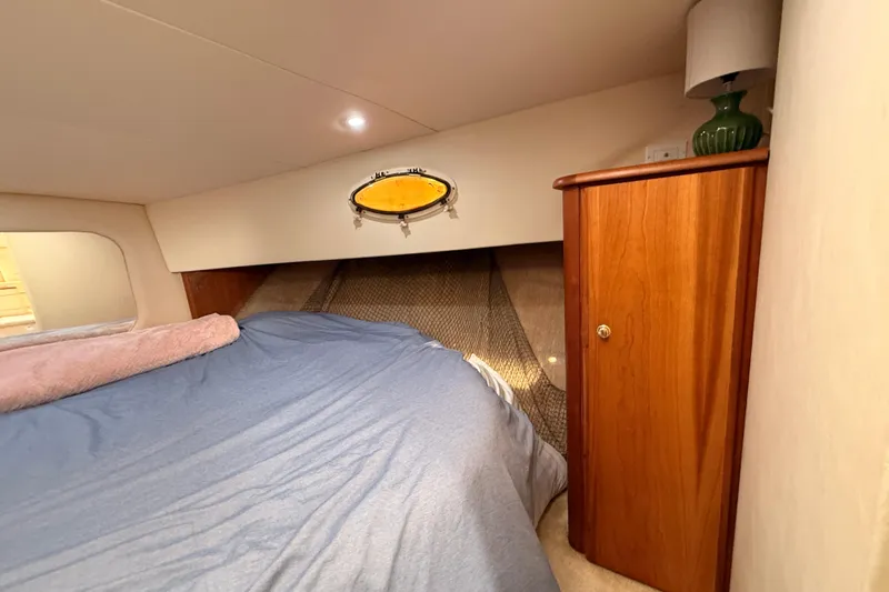  Yacht Photos Pics 1998 Silverton 40 Convertible cabin interior with bed, wooden cabinet, and porthole window.