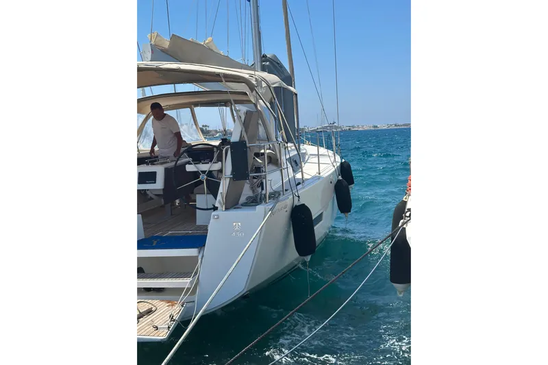  Yacht Photos Pics 2020 Dufour 430 sailboat docked in clear blue waters, with a person at the helm.