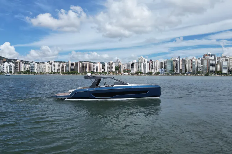  Yacht Photos Pics 2026 Schaefer V44 yacht cruising near a city skyline under a partly cloudy sky.