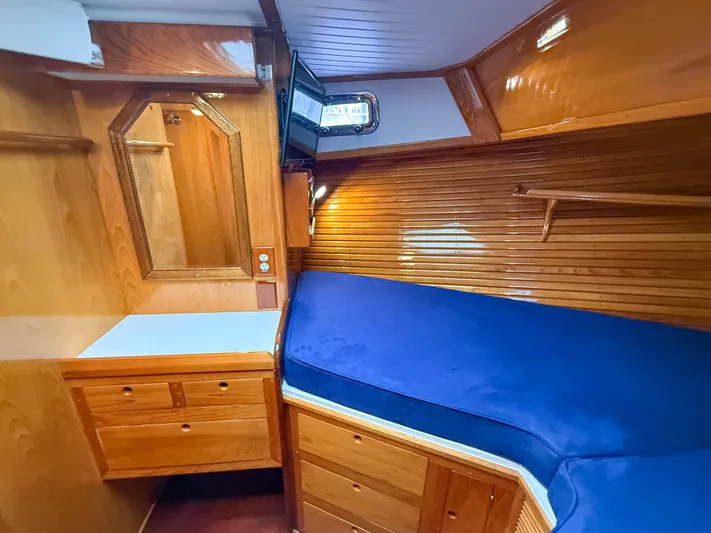 Argonaut Yacht Photos Pics Cozy cabin interior of 1984 Wilbur 38 with wooden finish and blue bedding.